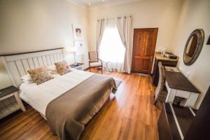 a bedroom with a bed and a desk and a window at AnnVilla Guesthouse in Klerksdorp