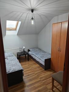 コニャクフにあるDom Koniakówのベッド2台、キャビネット、窓が備わる客室です。