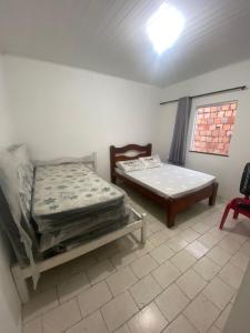 a bedroom with two mattresses and a bed and a window at casa grande e tranquila in Porto Seguro