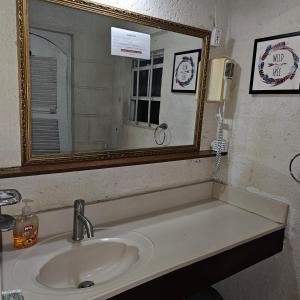 a bathroom sink with a mirror and a phone at David's Place in Christ Church