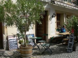 a tree in front of a cafe with tables and chairs at Hotel zum alten Schweizer in Twann