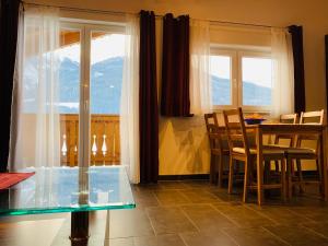 a dining room with a table and chairs and windows at Appartement inkl Gästekarte in Uttendorf