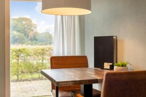 ein Esszimmer mit einem Tisch und einem großen Fenster in der Unterkunft Het Koetshuis in Ruurlo