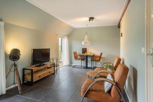 ein Wohnzimmer mit einem TV und einem Tisch in der Unterkunft Het Koetshuis in Ruurlo
