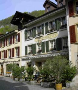 a large white building with green shutters on a street at Hotel zum alten Schweizer in Twann