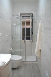 a white bathroom with a shower and a toilet at L' Isola di Bacco in Porto Cesareo