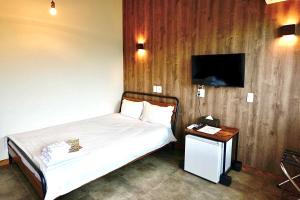 1 dormitorio con 1 cama y TV en la pared en リゾートイン西表島 en Iriomote