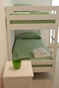 a white bunk bed with a table and a green bowl at L' Isola di Bacco in Porto Cesareo