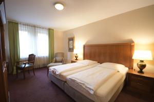 a hotel room with a large bed and a chair at Gästehaus Bavaria in Regensburg