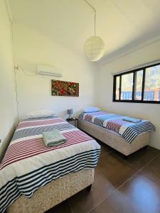 two beds in a room with two windows at Twin House #2 in Ponta do Ouro