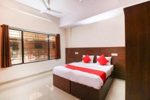 sypialnia z łóżkiem z czerwonymi poduszkami i oknem w obiekcie OYO The Royal International Hotel w mieście Bengaluru