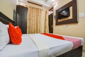 a bedroom with a bed with orange pillows and a tv at OYO Orange Residency in Chik Bānavar