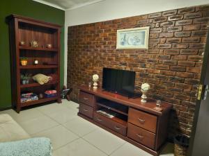 a living room with a tv on a brick wall at Monkey Heartland in Waterfall