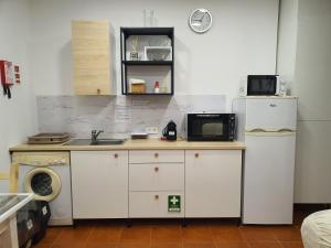eine Küche mit einer Spüle, einer Mikrowelle und einem Kühlschrank in der Unterkunft Zabava Sacavém in Sacavém