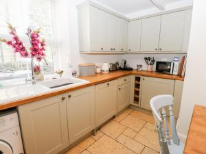 uma cozinha com armários brancos e um lavatório em The Cottage em Yeadon