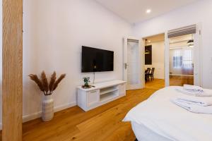 a white bedroom with a flat screen tv on a wall at The Chic One, Unirii Square View in Timişoara