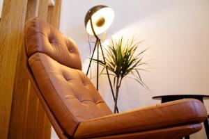a brown leather chair next to a lamp and a plant at The Chic One, Unirii Square View in Timişoara