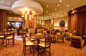 a restaurant with tables and chairs in a hotel lobby at Peermont Metcourt at Umfolozi, Empangeni in Empangeni