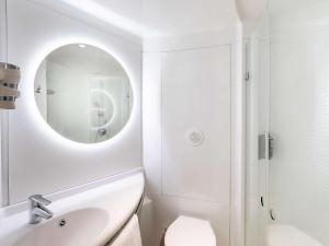 Baño blanco con lavabo y espejo en Hotel ibis Lisboa Alfragide en Lisboa