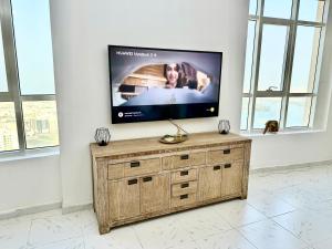 a flat screen tv sitting on top of a wooden dresser at Luxury Apartment 2BD 120m2 Al Majaz PS5, Pool, View Khalid Lac in Ras al Khaimah