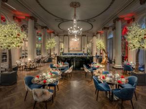 uma sala de jantar com mesas e cadeiras e um lustre em The Waldorf Hilton em Londres