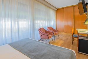 een kamer met stoelen, een bed en een bureau bij Hotel Castilla Vieja in Palencia