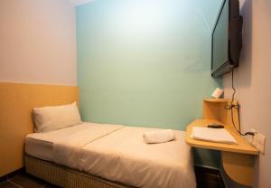 a small room with a bed and a television at JQ Station Eight Inn in Ipoh