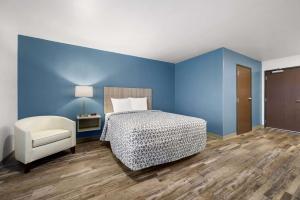 a bedroom with blue walls and a bed and a chair at WoodSpring Suites Dearborn Detroit in Dearborn