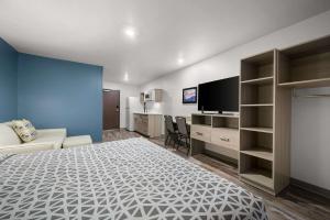a bedroom with a bed and a tv and a couch at WoodSpring Suites Dearborn Detroit in Dearborn