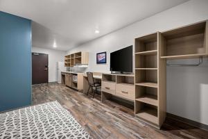 an office with a desk and a television in a room at WoodSpring Suites Dearborn Detroit in Dearborn