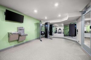 a gym with green walls and a flat screen tv at WoodSpring Suites Dearborn Detroit in Dearborn