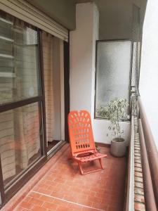 einem orangenen Stuhl auf dem Balkon eines Hauses in der Unterkunft Amplio departamento a dos cuadras del río Paraná, a tres de la peatonal y a seis del Monumento a la Bandera. Ambiente familiar. in Rosario