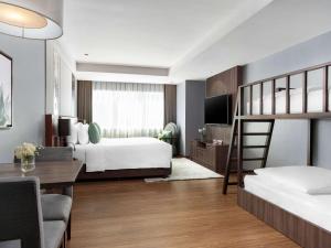 um quarto com 2 beliches e uma secretária em Novotel Living Bangkok Sukhumvit Legacy em Bangkok