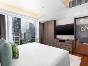 1 dormitorio con 1 cama blanca grande y ventana grande en Novotel Living Bangkok Sukhumvit Legacy, en Bangkok