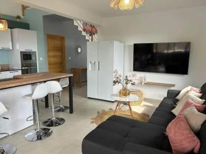 ein Wohnzimmer mit einem schwarzen Sofa und einer Küche in der Unterkunft Villa Idylle quatre etoiles in Rivière