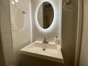 ein Badezimmer mit einem weißen Waschbecken und einem Spiegel in der Unterkunft NYC Oasis in Mott Haven