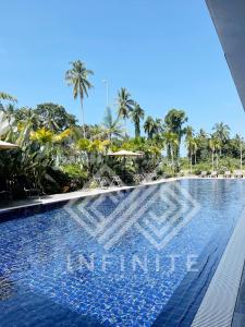 a swimming pool with palm trees in the background at Roxy Sematan Beach Townhouse Deluxe , 1 & 2 in Sematan
