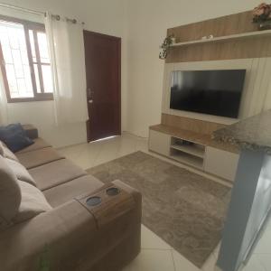 sala de estar con sofá y TV de pantalla plana en Casa de 2 Quartos na Praia da Joaquina, en Florianópolis