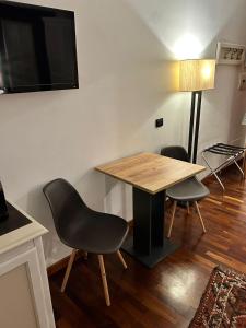 ローマにあるイン ローマ ルームズ & スイーツのテーブル、椅子2脚、テレビが備わる客室です。