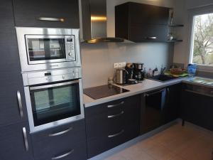 une cuisine avec des appareils électroménagers en acier inoxydable et des armoires noires dans l'établissement Appartement Merville-Franceville-Plage, 3 pièces, 6 personnes - FR-1-465-9, à Merville-Franceville-Plage