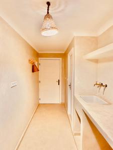 La salle de bains est pourvue d'un lavabo et d'une porte blanche. dans l'établissement Amazigh Home, à Mirleft