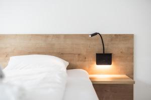 a bed with a lamp on a wooden headboard at myQuartier Innsbruck City Apartments in Innsbruck