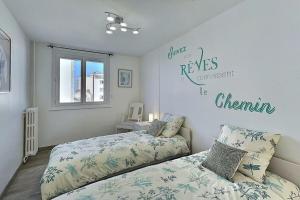 um quarto com duas camas e uma placa na parede em Le Voltaire | Balcon | Mon Groom Troyes em Troyes