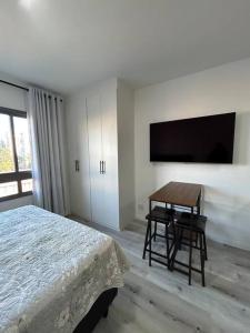 a bedroom with a bed and a table and a tv at Apartamento ao Lado do metrô Carrão in Sao Paulo