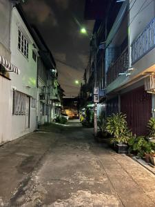 una strada vuota di notte con edifici e piante di Achcha Family Hotel a Bangkok