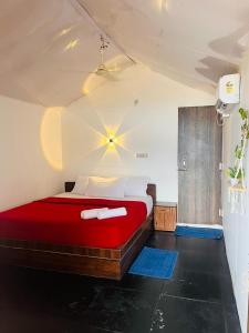 1 dormitorio con 1 cama con sábanas rojas y almohadas blancas en Casa fiesta Sea front beach huts, en Patnem