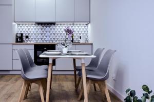 a white kitchen with a table and chairs at VacationClub - Old Town Apartament 11 in Kłodzko
