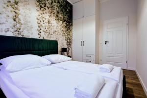 sypialnia z 2 łóżkami z białą pościelą i zielonym zagłówkiem w obiekcie VacationClub - Old Town Apartament 5 w Kłodzku