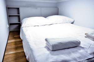 uma cama branca com lençóis brancos e almofadas em VacationClub - Old Town Apartament 2 em Klodzko