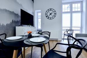 uma sala de jantar com mesa e cadeiras e um relógio em VacationClub - Old Town Apartament 2 em Klodzko